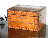 Closed walnut writing box showing intricate geometric inlay pattern on front, with mother-of-pearl center diamond