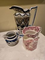 Three vintage collectible jugs: Wedgwood blue & white creme jug, Masons Ironstone pink jug, Royal Danish blue and brown patterned pitcher