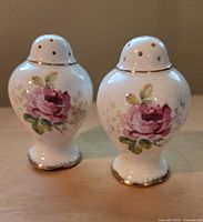Photo of a pair of white ceramic Wedgwood salt and pepper shakers decorated with pink rose flowers and gold trim.