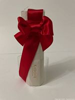 Front view of Burberry Body perfume bottle wrapped with a red satin bow inside a clear box.
