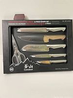 Front view of the packaged 5 piece Cangshan Sanford Series cutting utensil set showing 4 knives with sheaths and one pair of scissors in black plastic packaging.