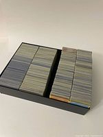 Black container with four thick stacks of trading cards, two stacks with light gray backs, two with mixed colored edges