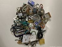 Pile of assorted costume jewelry including bracelets, necklaces, earrings, and pendants in various styles and colors.