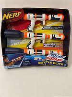 Front view of three Nerf Super Soaker Bottle Blitz water blasters in original package showing trademark Nerf branding and three water blasters in white, orange, and black.