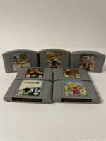 7 Nintendo 64 game cartridges arranged on table, titles visible in subsequent photos