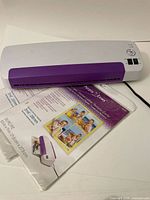 Top view of the Purple Cows laminator with part of laminating pouches package shown beneath it.