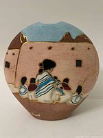 Front view showing a woman with children and a lamb near adobe buildings under a blue sky, signed Russell on lower left.