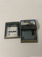 Front view of Metal Gear Solid and Top Gear Pocket Nintendo Game Boy Color game cartridges on a surface.