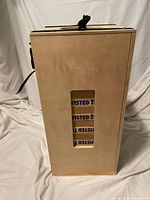 Side view of the wooden carrying case showing stacked Twisted Tea branded Jenga blocks inside.