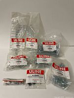 Photo of several sealed plastic bags containing Uline pegboard hooks and mounting hardware labeled with model numbers including H-2686.