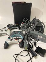 Xbox 360 console, four controllers, power brick, and cables arranged on a white surface.