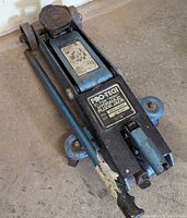 Full view of Pro-Tech hydraulic floor jack with handle and wheels on concrete floor.