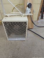Front view of the white metal space heater with mesh grille and attached power cord.