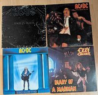 Four vinyl records arranged in a 2x2 grid showing AC/DC Back in Black, If You Want Blood, Who Made Who and Ozzy Osbourne Diary of a Madman.