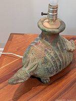 Close-up image showing ceramic armadillo lamp base with detailed hand decoration and lamp bulb socket mounted at the top.