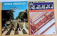 Photo showing the front covers of four vinyl LP records: Wings Greatest, A Hard Day's Night, The Beatles 1962 to 1966, and Abbey Road (early pressing).