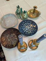 Overview of all items on white tablecloth including brass Wedgwood candlesticks, ceramic plates, and the oil and vinegar set