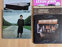 Four Elton John vinyl LP records laid out showing album cover artwork: Tumbleweed Connection, A Single Man, Don't Shoot Me I'm Only the Piano Player, and self-titled album.