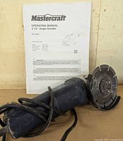 Photo of Mastercraft operating manual and angle grinder with attached diamond blade.