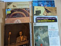 Photo of a stacked group of vintage jazz LP vinyl covers including artists such as Dave Brubeck, Paul Desmond, Sidney Bechet, Mingus, and Dukes of Dixieland.