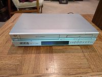 Front view of silver JVC HR-XVC23U DVD and VCR combo player with control buttons and VHS/DVD ports