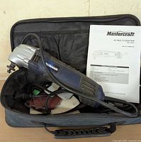 Mastercraft AC Multi-Crafter multitool lying in black carrying case with owner's manual and sanding discs visible inside.