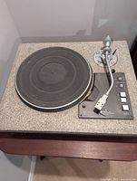 Front view of turntable showing granite plinth, platter mat, control panel and tonearm.