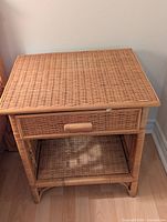 Front view of one rattan bedside table showing woven top, drawer and open shelf