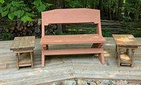 Front view of hand-made red painted pine bench with matching two small pine side tables placed on wooden deck outdoors.