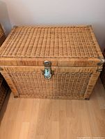Front view of rattan chest showing woven wicker texture and metal clasp lock.