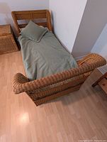 Top-down three-quarter view of bed with green duvet and pillow.