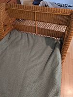 Close-up of rattan curved headboard and partial bedding