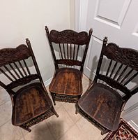 Three matching pressed back chairs arranged in a corner, showing overall condition and shape.