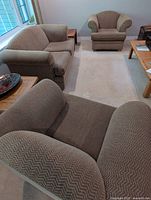 Three-piece set comprising loveseat and two armchairs arranged in living room.