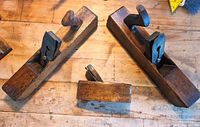 Three wooden hand planes displayed on a wooden surface including the large Marples smoothing plane, a Greenslade block plane, and a small unmarked block plane.