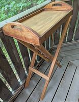 Wooden tray elevated on its folding legs stand showing side view of tray handles and legs structure.