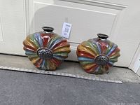 Two colorful glazed pots placed side by side on the ground in front of a door, ruler in front for scale