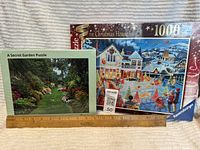 Both new sealed puzzles: Lee Valley A Secret Garden and Ravensburger Limited Edition The Christmas House 1000-piece puzzle shown with ruler for size reference.