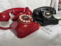 Photo of two rotary dial telephones side by side, red Grand Phone and black Northern Electric model 8-8114.