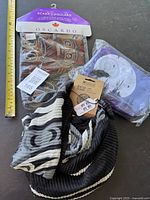Lot includes two scarves: one soft light Oscardo scarf with Indigenous art in packaging, one long recycled bottle scarf with black and grey design; plus a small canvas tote bag with raven moon design in packaging.