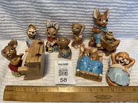 Nine vintage woodland animal figurines arranged in two rows with a wooden ruler in front for scale, measuring about 3 to 6 inches tall, showing paint and glaze finish.