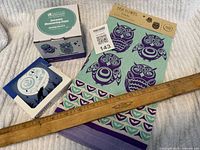 All items together including the measuring cups box, coaster box, and tea towel with owl designs and rulers for scale.