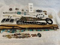 Photo of the entire assortment of jewelry items including necklaces, earrings, bracelets, and brooch set spread on white background with ruler for scale.