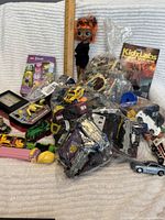 Image showing all items spread on a surface including bags of LEGO, metal toy cars, PEZ dispensers, vintage handheld game, KidzLabs Pocket Volcano kit, Taylor Swift sticker pack, and a doll.