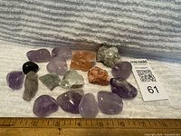 Lot of 17 assorted stones and gemstones including amethyst and other various stones with ruler showing size approximately 1-2 inches.