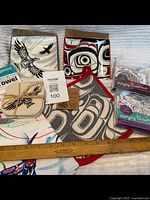 Full lot overview showing plates, coasters, oven mitt, hanging ornaments, tea towel with ruler for size reference