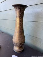 Front angled view of the tall etched brass vase showing entire shape and detailed etching.