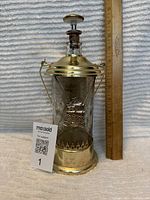 Full view of vintage glass musical decanter with ruler for scale and maxsold auction tag