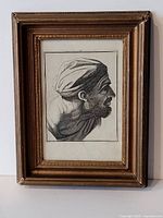 Framed black and white engraving of a bearded man in profile wearing a headwrap, set in a gold-tone frame.