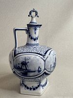 Front and side view of the antique Delft wine jug showing windmill scene and floral accents